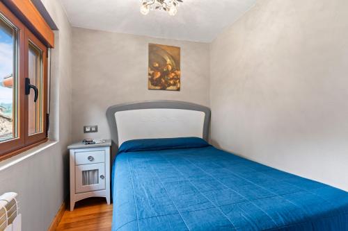 a small bedroom with a bed with a blue bedspread at El Bosque in Candamo
