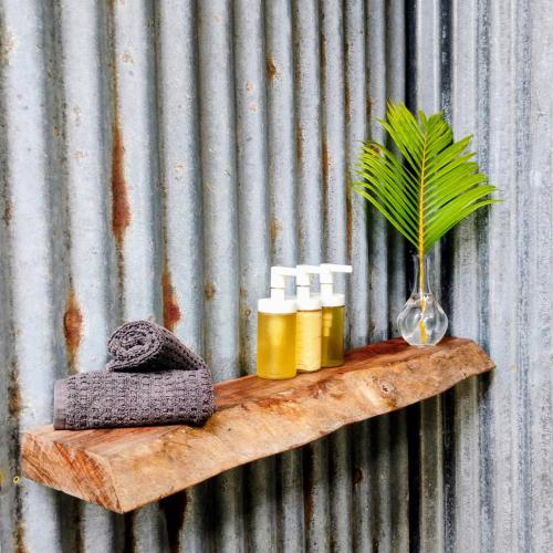 Un estante de madera con tres botellas y una planta encima. en Zen Den, en Rincón