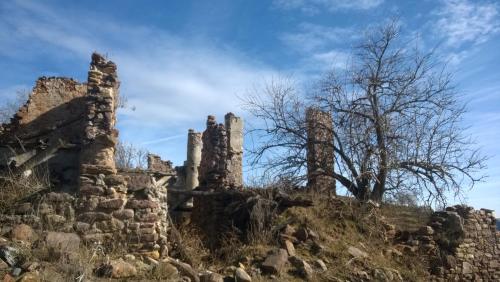 an old stone building on a hill with a tree at La Faiada in El Pont de Suert