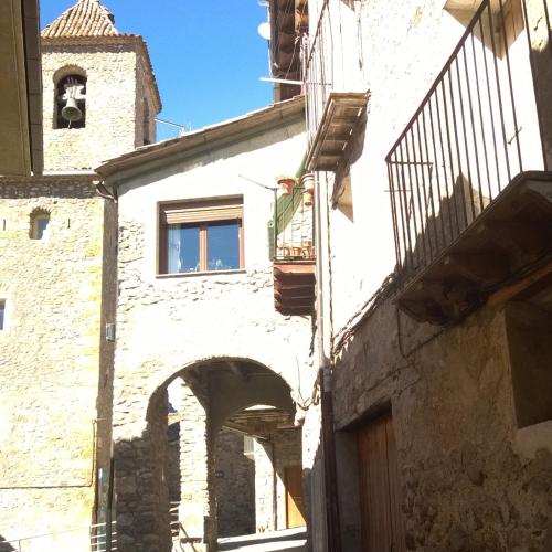 an alley in an old building with a clock tower at La Faiada in El Pont de Suert