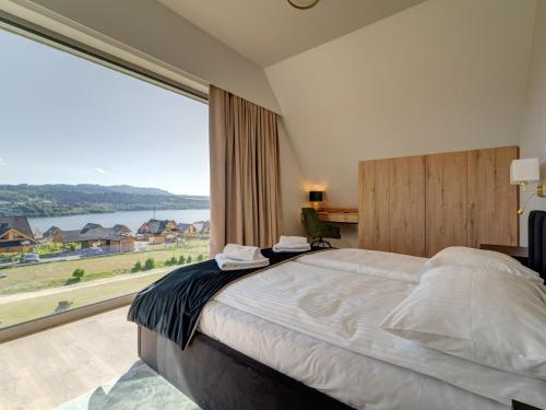 a bedroom with a large bed with a large window at Apartament Panorama Lake & Ski in Kluszkowce