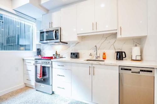 a white kitchen with white cabinets and appliances at Inviting 2BR Basement Suite in Downtown Toronto - The Roland in Toronto