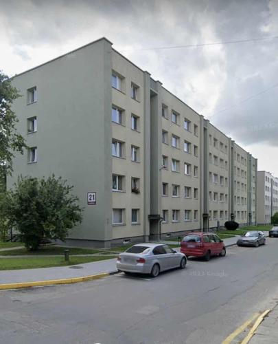 a large white building with cars parked in a parking lot at Namų mūza "A" SELF CHECK IN in Plungė
