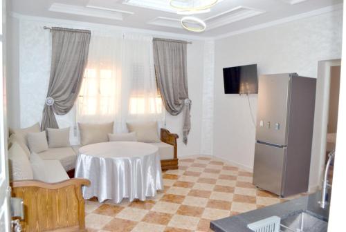a living room with a table and a refrigerator at Apartment 5 min Corniche in Nador