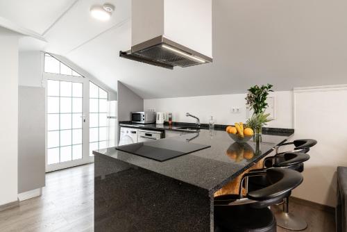 a kitchen with a counter with black chairs in it at Barreiro View in Ribeira Brava