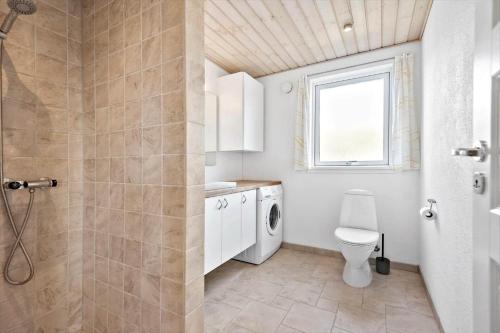 a bathroom with a toilet and a washer and dryer at 503-Hvide-Sande-Sonder-Klitvej-129 in Havrvig