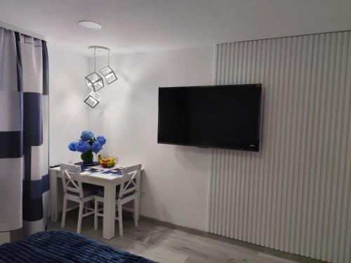 a room with a table and a television on a wall at Apartament Premium Tarnów 2 in Tarnów