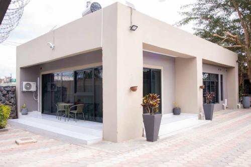 a white house with glass doors and a patio at Kuwunda Apartments in Lusaka