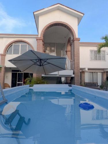 an umbrella sitting in a swimming pool in front of a house at Adventure Inn La Paz in La Paz