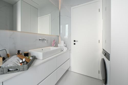 ein weißes Badezimmer mit Waschbecken und Spiegel in der Unterkunft Kalma Luxury Living Suites Heraklion in Iraklio