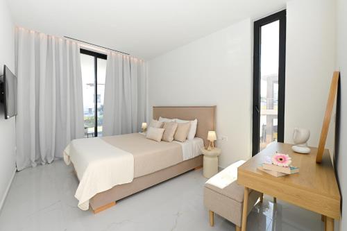 ein weißes Schlafzimmer mit einem Bett und einem Schreibtisch in der Unterkunft Kalma Luxury Living Suites Heraklion in Iraklio