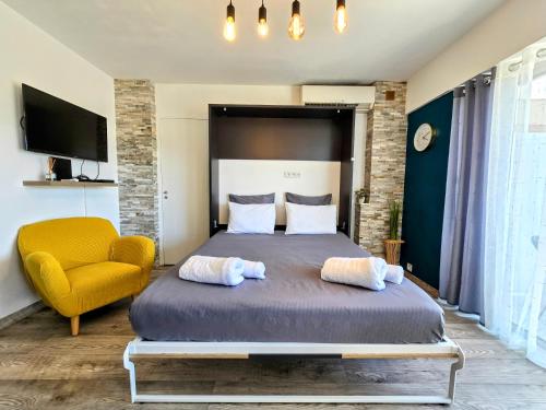 a bedroom with a bed and a yellow chair at Beachfront - Panoramic View - Balkony - AC in Cagnes-sur-Mer
