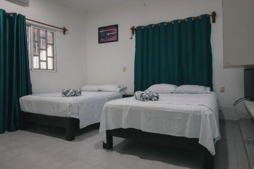 two beds in a room with green curtains at Zayali Bacalar - Guest House in Bacalar