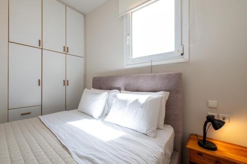 a bedroom with a bed with white sheets and a window at Mythos Suites-Poseidon apartment in Methoni