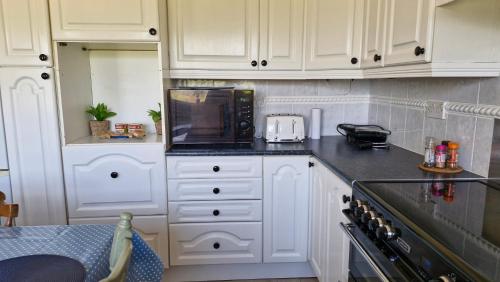 a kitchen with white cabinets and a black counter top at The Yoke Apt Peaceful Private Garden views in Ballybrittas