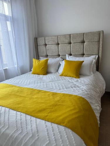 a bed with two yellow pillows on it at Homely Stays, Ruaka in Nairobi