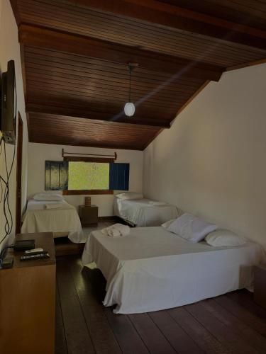 a bedroom with two beds and a table and a tv at Pousada Bons Ventos in Paraty