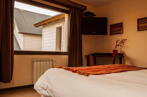 a bedroom with a bed and a large window at Hotel Poincenot in El Chalten