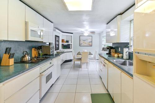 a large kitchen with white cabinets and a table at Tranquil and Pet-Friendly Estate on Long Island! in Hauppauge