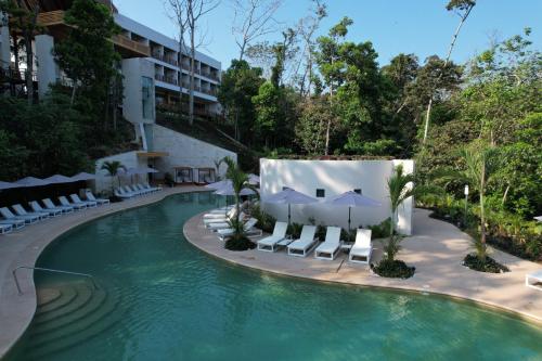a pool at a hotel with chairs and umbrellas at Hotel Mundo Maya Palenque in Palenque
