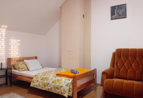 a small bedroom with a bed and a chair at Kuća Amazonija in Apatin