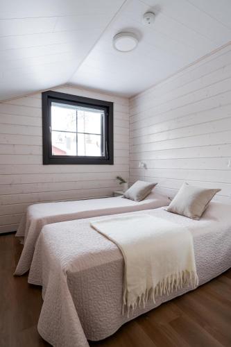 two beds in a room with a window at Auroralevi Suites Sointuilevi, Log Cabin, Central, Sauna, 2 ski passes included in Levi