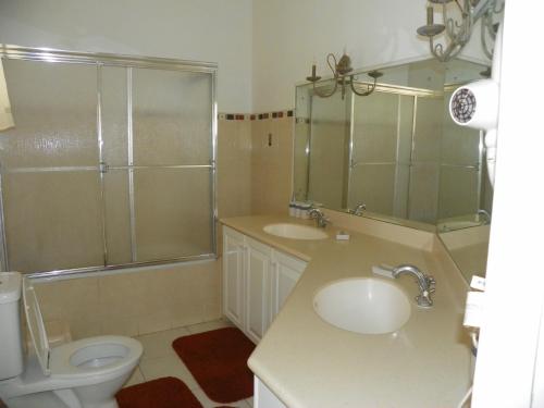a bathroom with a toilet and a sink and a shower at AnnJenn Apartments in Christ Church