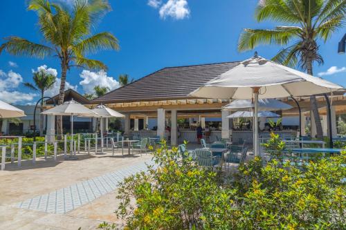 a patio with umbrellas and chairs and palm trees at Viva Miches by Wyndham, a Trademark All Inclusive Resort in Miches