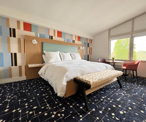 a bedroom with a large bed with a bench in it at Colony House Motor Lodge in Roanoke
