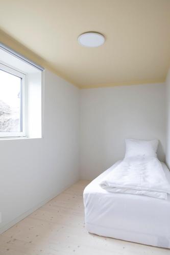 a white bedroom with a bed and a window at Ny og moderne leilighet i Bodø Sentrum! in Bodø