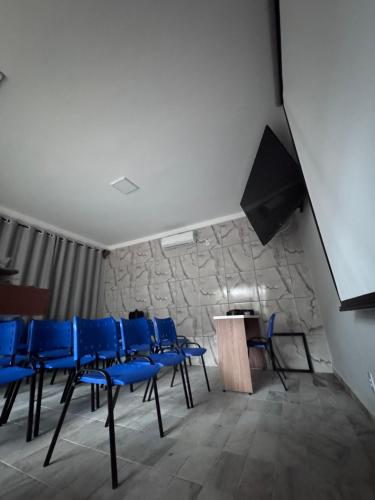a meeting room with blue chairs and a podium at Hotel Coqueiros in Valparaíso de Goiás