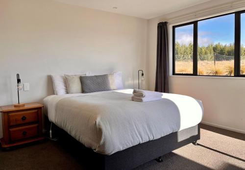a bedroom with a large bed with a window at Starview 88 - Lake Tekapo in Lake Tekapo