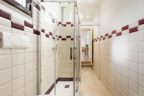 a glass shower in a bathroom with white tiles at GIOSAHOUSE in Uggiano la Chiesa