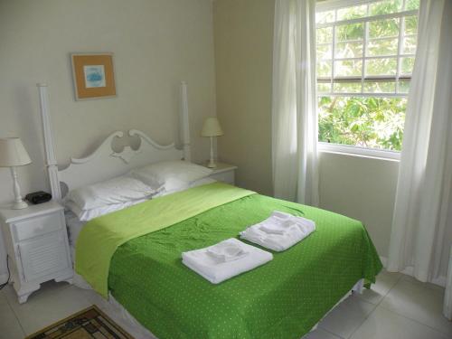 a bedroom with a green bed with two towels on it at AnnJenn Apartments in Christ Church