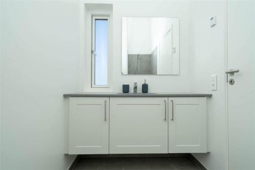 Un baño blanco con lavabo y espejo. en 902-Hvide-Sande-Langsand-98-1-sal, en Hvide Sande