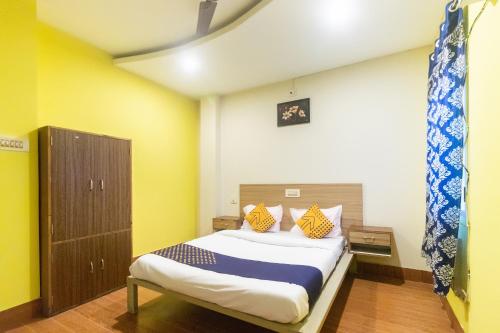 a bedroom with a bed with yellow walls at Hotel O Prabir Residency Inn in Urāli