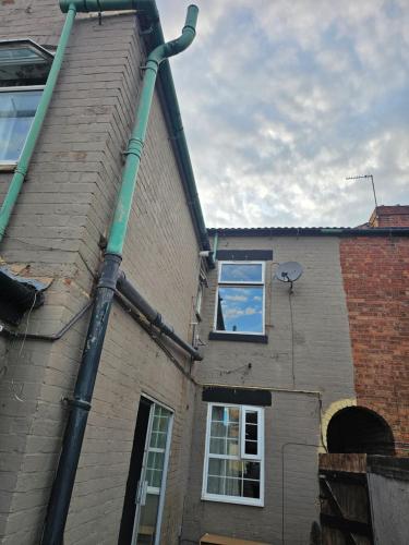 a green pipe on the side of a building at Centrally located house, Rm 4 big in Burton upon Trent