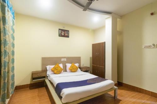 a bedroom with a bed with yellow pillows on it at Hotel O Prabir Residency Inn in Urāli