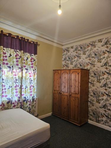 a bedroom with a bed and a dresser and curtains at Centrally located house, Rm 4 big in Burton upon Trent