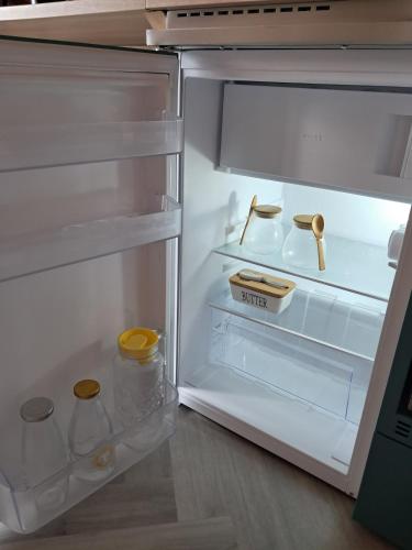 an open refrigerator with its door open and empty shelves at Beinn View Pod in Corpach
