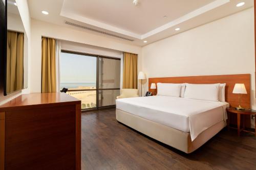 a bedroom with a white bed and a large window at Holiday Inn - Suites Kuwait Salmiya by IHG in Kuwait