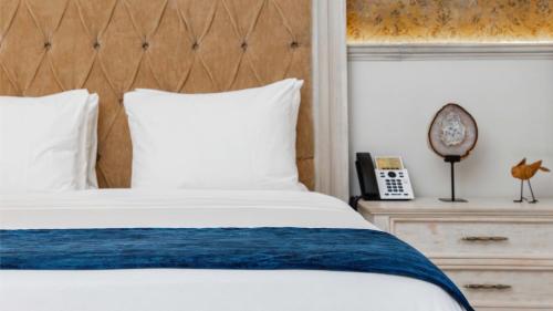 a bedroom with a bed and a clock on a night stand at voco Royalty Puebla Downtown by IHG in Puebla