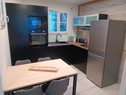 a kitchen with a table and a stainless steel refrigerator at Chalet vue lac à 200 mètres des remontées in Les Angles