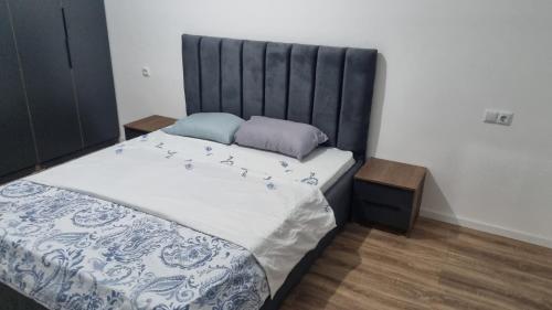 a bedroom with a large bed with a black headboard at Etno apartmemt in Prishtinë