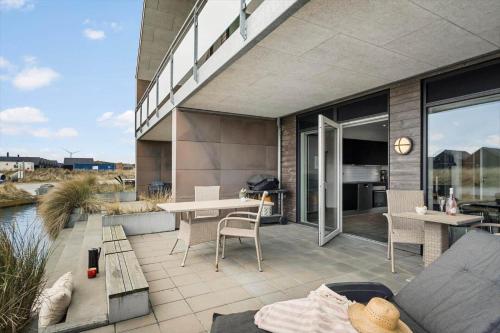 a patio with a table and chairs and a building at 9928-Hvide-Sande-Langsand-86 in Hvide Sande