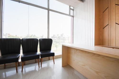 two chairs sitting next to a counter in a room with windows at Super Hotel o Shivaay Phase 1 Mohali Bus Terminal in Sohāna