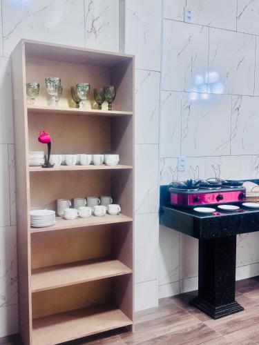 a cupboard with dishes and a stove in a kitchen at Hotel Coqueiros in Valparaíso de Goiás