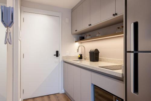 a kitchen with white cabinets and a sink at Skyline Parque Moinhos by LikeHome in Floresta