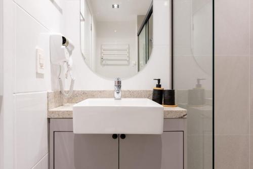a white bathroom with a sink and a mirror at Skyline Parque Moinhos by LikeHome in Floresta