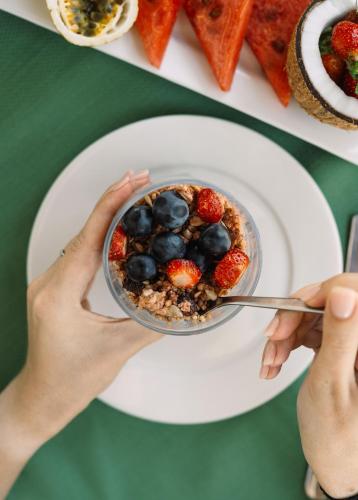 une personne tenant un bol de granola et de baies sur une assiette dans l'établissement The Soul Zanzibar Beach Hotel & Spa, à Pwani Mchangani Mdogo
